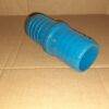 Conector plástico azul sobre fundo marrom, com forma cilíndrica e superfícies estriadas.
