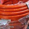 Mangueiras de limpeza de alta pressão na cor laranja, empilhadas em rolo.